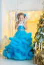 Young beautiful girl in blue white elegant evening dress sitting on floor near christmas tree and presents on a new year Royalty Free Stock Photo