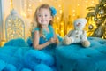 Young beautiful girl in blue white elegant evening dress sitting on floor near christmas tree and presents on a new year Royalty Free Stock Photo