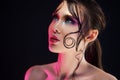 Young beautiful girl bright makeup with a wet look shine, dark background, pink light, disco style Royalty Free Stock Photo