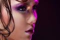 Young beautiful girl bright makeup with a wet look shine, dark background. Profile close-up Royalty Free Stock Photo