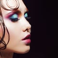 Young beautiful girl bright makeup with a wet look shine, dark background. Profile close-up Royalty Free Stock Photo