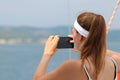 A young beautiful girl with a brown-haired woman takes a photo of a smartphone on the sea from the side of a sailing yacht. A fasc