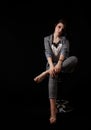 Young beautiful girl in a business suit posing sitting on chair Royalty Free Stock Photo