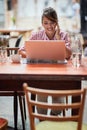 Young beautiful girl at a cafe relaxed working on laptop Royalty Free Stock Photo