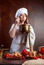 Young woman in a chef uniform with old brass pan and wooden spoon Royalty Free Stock Photo