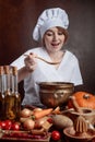 Young beautiful girl in a chef uniform with pan and wooden spoo Royalty Free Stock Photo