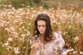 Young beautiful girl with closed eyes in white dress smelling flowers in chamomile field Royalty Free Stock Photo