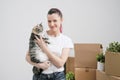 Young beautiful girl with colored hair in a white T-shirt and jeans, holding a pet cat and looking out the window Royalty Free Stock Photo