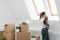 Young beautiful girl with colored hair in a white T-shirt and jeans, holding a pet cat and looking out the window Royalty Free Stock Photo