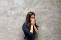 Young beautiful girl covers her nose with hands over grey background