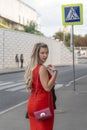 Young beautiful girl with curvy body shape standing on street background wearing red close fitting sleeveless dress Royalty Free Stock Photo