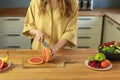 Young beautiful girl is cutting a grapefruit. Royalty Free Stock Photo
