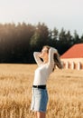 A young beautiful girl in a denim skirt walks through a wheat field on a sunny day Royalty Free Stock Photo