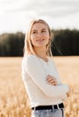 Young beautiful girl in a denim skirt walks through a wheat field on a sunny day Royalty Free Stock Photo