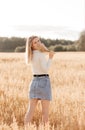 A young beautiful girl in a denim skirt walks through a wheat field on a sunny day Royalty Free Stock Photo