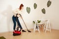 A young girl doing cleaning in the house. A woman vacuums the floor with a vacuum cleaner. Copy space. Listens to music Royalty Free Stock Photo