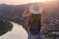 Young beautiful girl in dress and hat, looking at river and city sunset Royalty Free Stock Photo