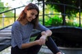 Young and beautiful girl dressed in gray putting on a gold and quartz watch