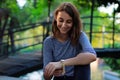 Young and beautiful girl dressed in gray putting on a gold and quartz watch