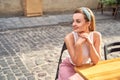 Young beautiful girl dressed in retro vintage style in the old european city sitting on the street cafe wooden table Royalty Free Stock Photo