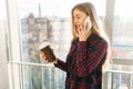 Young beautiful girl drinking coffee and talking on the phone, a woman in an office building Royalty Free Stock Photo