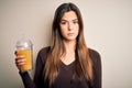 Young beautiful girl drinking glass of healthy orange juice over isolated white background with a confident expression on smart Royalty Free Stock Photo