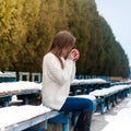 Young beautiful girl drinking tea in a cool winter park