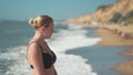 young beautiful girl in the early morning warms her back under the sun on the black sea coast