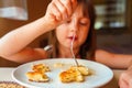 Young beautiful girl eating cheesecakes for breakfast. Selective focus Royalty Free Stock Photo