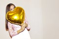 Young beautiful girl embracing heart shaped golden air balloon. valentines day, birthday, womens day, anniversary, holiday Royalty Free Stock Photo