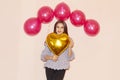 Young beautiful girl embracing heart shaped golden air balloon. valentines day, birthday, womens day, anniversary, holiday Royalty Free Stock Photo