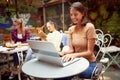 A young beautiful girl is enjoying a chat on a laptop while sitting in the bar. Leisure, bar, outdoor Royalty Free Stock Photo