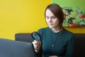 A young beautiful girl of European appearance in a blue jacket sitting in a cafe and working on a laptop on the couch against the Royalty Free Stock Photo