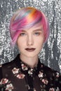 Young beautiful girl with freckles. Colored hair, blue, yellow, red, lilac and pink. Pixie Bob Haircut Gray background