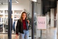 Young beautiful girl goes out clothing store with purchases. Season sale happy young adult female Royalty Free Stock Photo