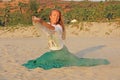 Young and beautiful girl in a green skirt pours sand through her