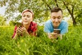 Young beautiful girl and guy lies on green grass and dandelions and talking smartphones Royalty Free Stock Photo