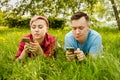Young beautiful girl and guy lies on green grass and dandelions and talking smartphones Royalty Free Stock Photo