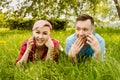 Young beautiful girl and guy lies on green grass and dandelions and talking smartphones Royalty Free Stock Photo