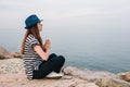 Young beautiful girl in a hat practicing yoga and meditating on stones next to the sea. Recreation. Vacation. Relaxation Royalty Free Stock Photo