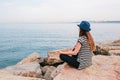 Young beautiful girl in a hat practicing yoga and meditating on stones next to the sea. Recreation. Vacation. Relaxation Royalty Free Stock Photo