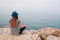 Young beautiful girl in a hat practicing yoga and meditating on stones next to the sea. Recreation. Vacation. Relaxation Royalty Free Stock Photo