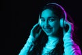 Young beautiful girl in headphones isolated on dark background in neon light Royalty Free Stock Photo