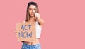Young beautiful girl holding act now banner pointing with finger to the camera and to you, confident gesture looking serious Royalty Free Stock Photo