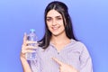 Young beautiful girl holding bottle of water smiling happy pointing with hand and finger Royalty Free Stock Photo