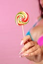 A young beautiful girl holding a colorful bright Lollipop photographed in close-up. on a pink isolated background. with copyspace Royalty Free Stock Photo