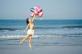 Young and beautiful girl holding helium balloons air, running and jumping for joy at the sea. holiday and vacation Royalty Free Stock Photo