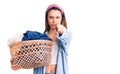 Young beautiful girl holding laundry basket pointing with finger to the camera and to you, confident gesture looking serious Royalty Free Stock Photo