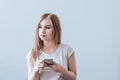 Young beautiful girl holding a mobile phone in her hands. Looking away Royalty Free Stock Photo