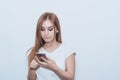 Young beautiful girl holding a mobile phone in her hands. Looks surprised at the screen